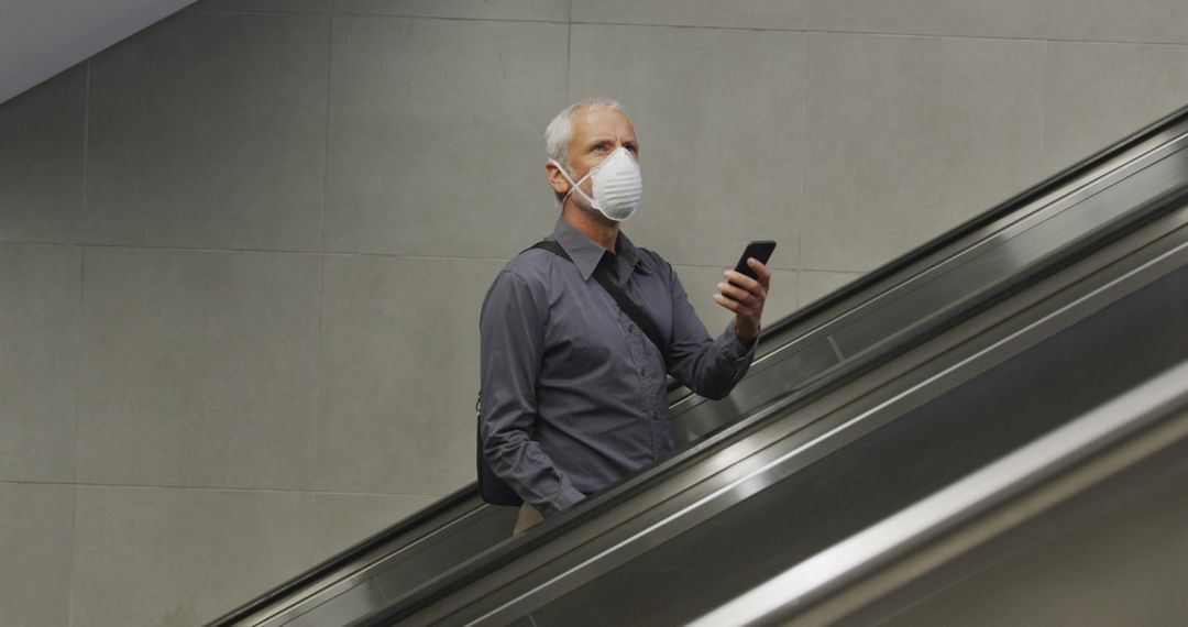 Businessman Wearing Face Mask Using Smartphone on Escalator - Free Images, Stock Photos and Pictures on Pikwizard.com