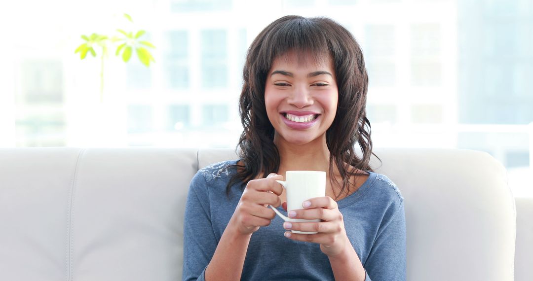 Smiling Young Woman Enjoying Morning Coffee on Couch - Free Images, Stock Photos and Pictures on Pikwizard.com