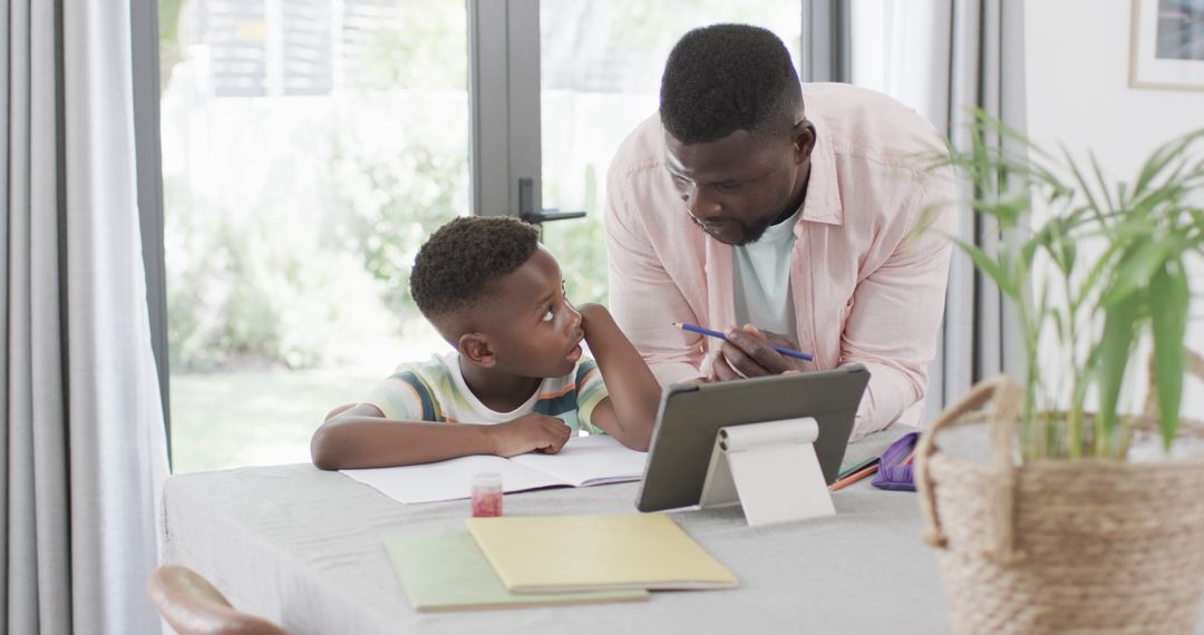 Father Assisting Son with Homework at Home Using Tablet