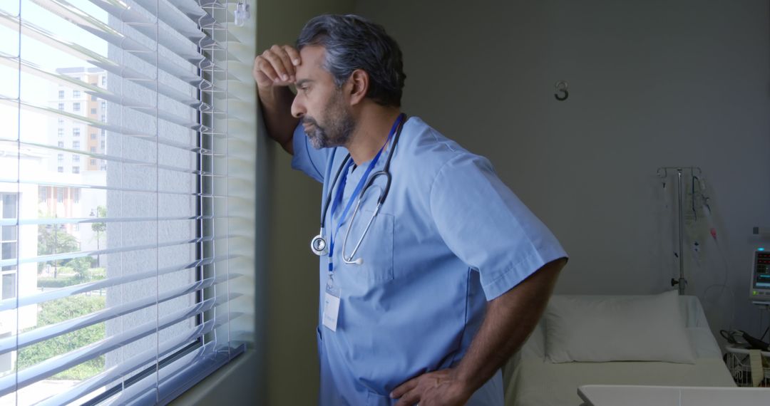 Concerned Healthcare Professional Looking Out Window in Hospital Room - Free Images, Stock Photos and Pictures on Pikwizard.com