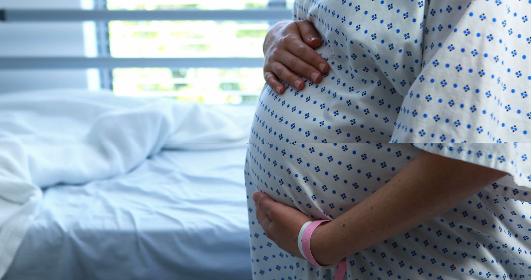 Pregnant Woman in Hospital Gown Holding Belly in Maternity Room - Free Images, Stock Photos and Pictures on Pikwizard.com