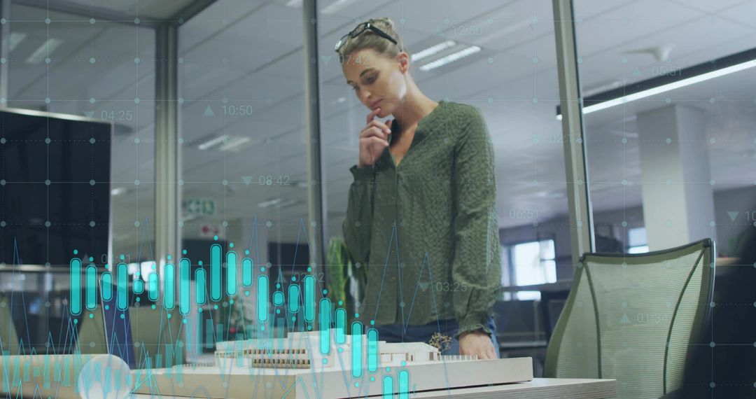 Architect reviewing scale model with data visualization in modern glass office