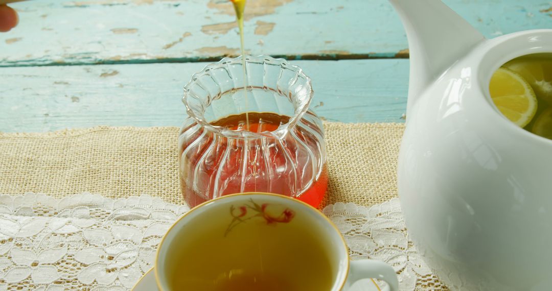 A cozy tea time scene is depicted with tea being poured and honey on a rustic table. - Free Images, Stock Photos and Pictures on Pikwizard.com