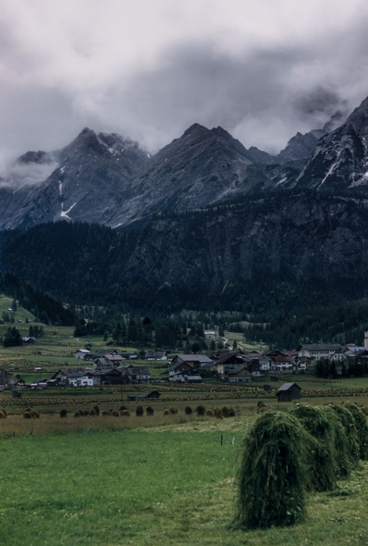 Scenic View of Alpine Village with Mountain Range and Clouds - Free Images, Stock Photos and Pictures on Pikwizard.com