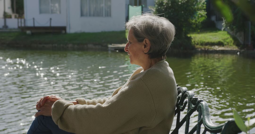 Elderly Woman Relaxing by the Lake in Sunshine - Free Images, Stock Photos and Pictures on Pikwizard.com