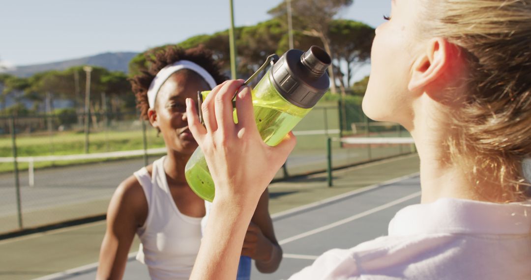 Image of happy diverse female tennis players talking and drinking water - Free Images, Stock Photos and Pictures on Pikwizard.com