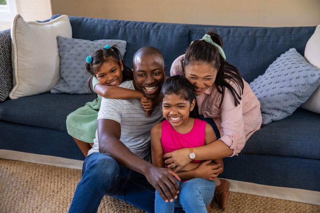 Happy Family Hugging on Carpet Near Blue Sofa in Living Room