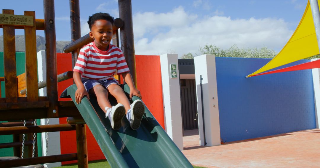 Happy African American Boy Enjoying Slide at School Playground