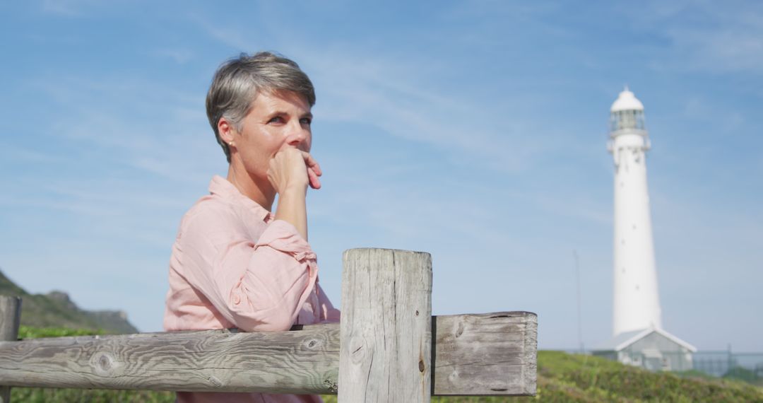 Contemplative Woman Sitting by Coastal Lighthouse - Free Images, Stock Photos and Pictures on Pikwizard.com