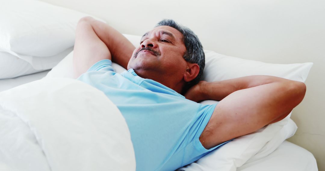 Middle-aged Man Resting in Bed with Hands Behind Head - Free Images, Stock Photos and Pictures on Pikwizard.com