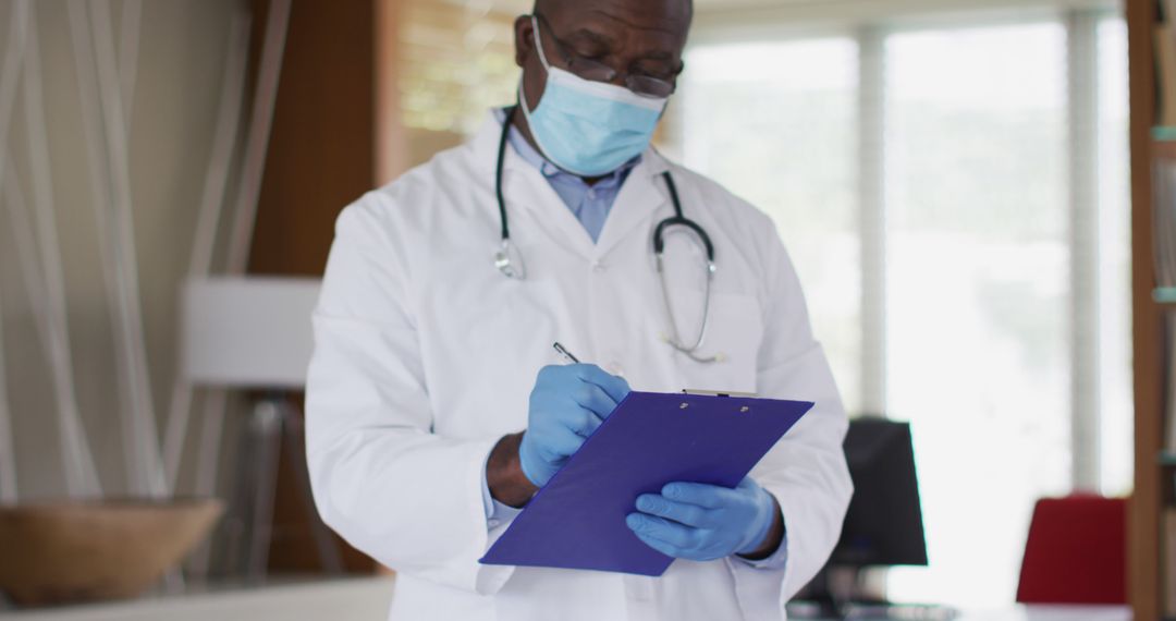 Senior African American Doctor Writing on Clipboard Wearing Medical Mask - Free Images, Stock Photos and Pictures on Pikwizard.com