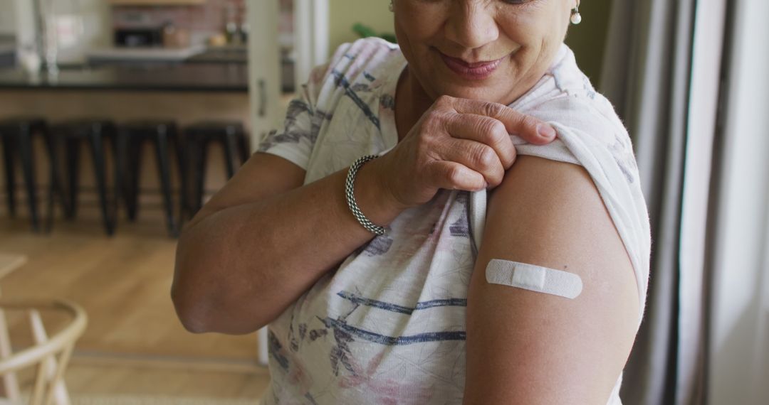 Smiling Woman Showing Arm with Bandage at Home After Vaccination - Free Images, Stock Photos and Pictures on Pikwizard.com