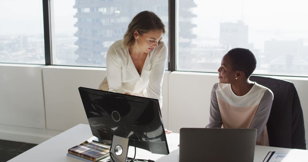 Diverse Female Colleagues Discussing Over Laptop in Modern Office