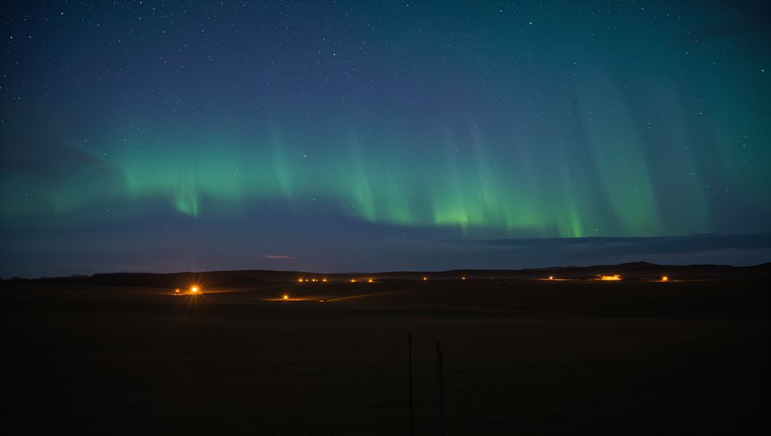 Emerald Aurora Borealis Stretching Over Remote Farmland Above Starry Night with Farm Lights