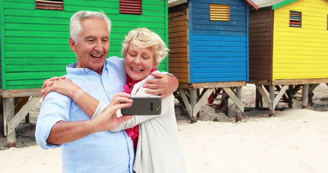 Senior Couple Taking Selfie On Beach Near Colorful Huts - Free Images, Stock Photos and Pictures on Pikwizard.com