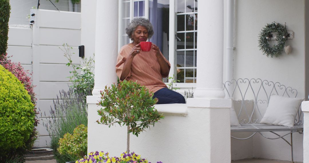 Senior african american woman drinking coffee while sitting on the porch of the house - Free Images, Stock Photos and Pictures on Pikwizard.com