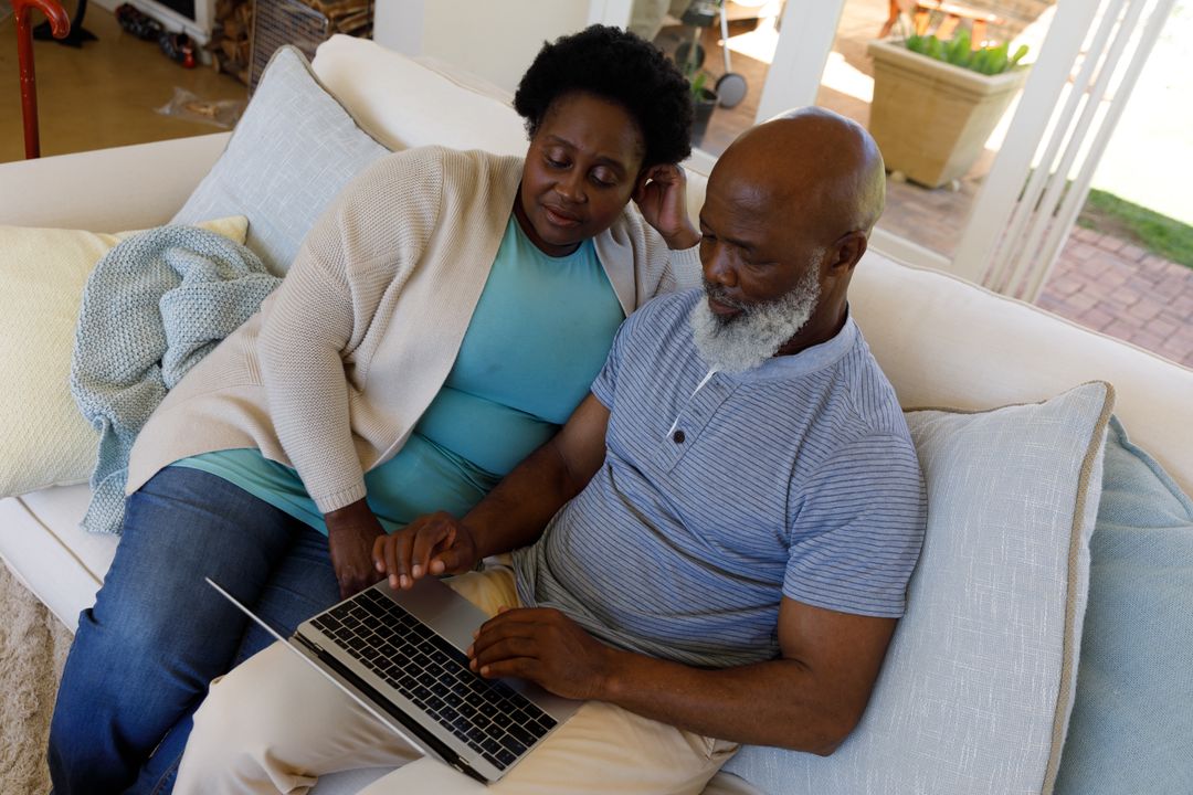 An african american senior couple sitting on the couch looking at a laptop - Free Images, Stock Photos and Pictures on Pikwizard.com