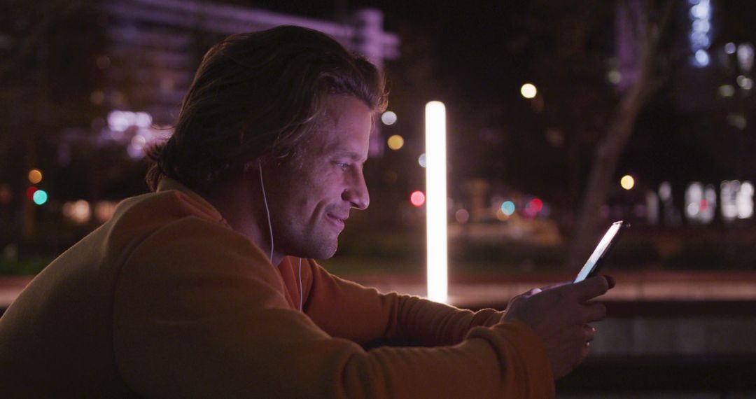 Man Smiling While Using Smartphone Outdoors at Night - Free Images, Stock Photos and Pictures on Pikwizard.com