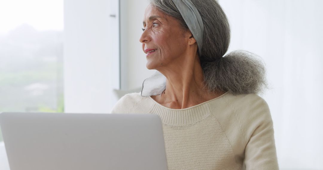 Older Woman Using Laptop By Window in Bright Room - Free Images, Stock Photos and Pictures on Pikwizard.com