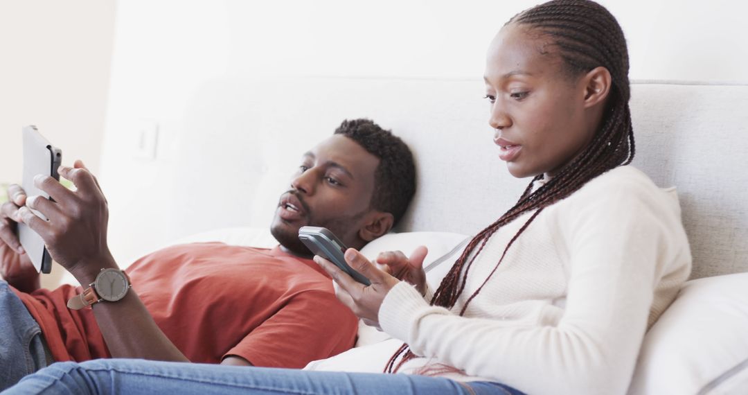 Couple Relaxing with Tablet and Smartphone in Modern Bedroom