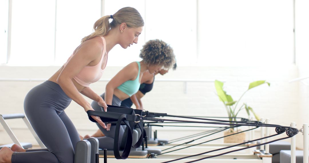 Women Exercising on Pilates Reformer Machines in Studio