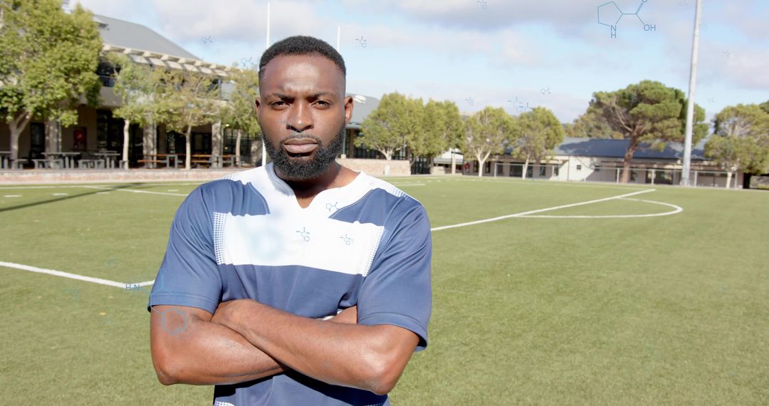 Confident soccer player standing with arms crossed on turf field focused portrait