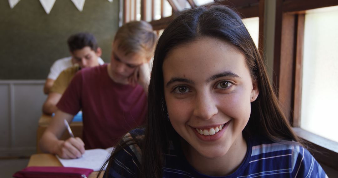Smiling Teenage Girl in Classroom with Peers Studying Behind