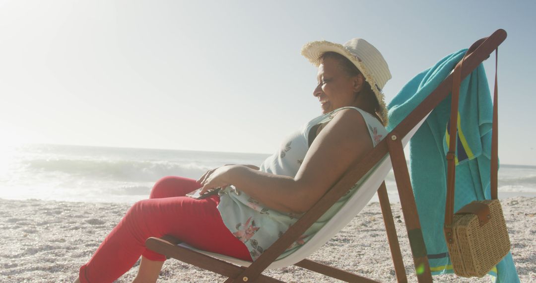 Senior Woman Relaxing in Beach Chair Under Sun Hat at Seaside - Free Images, Stock Photos and Pictures on Pikwizard.com