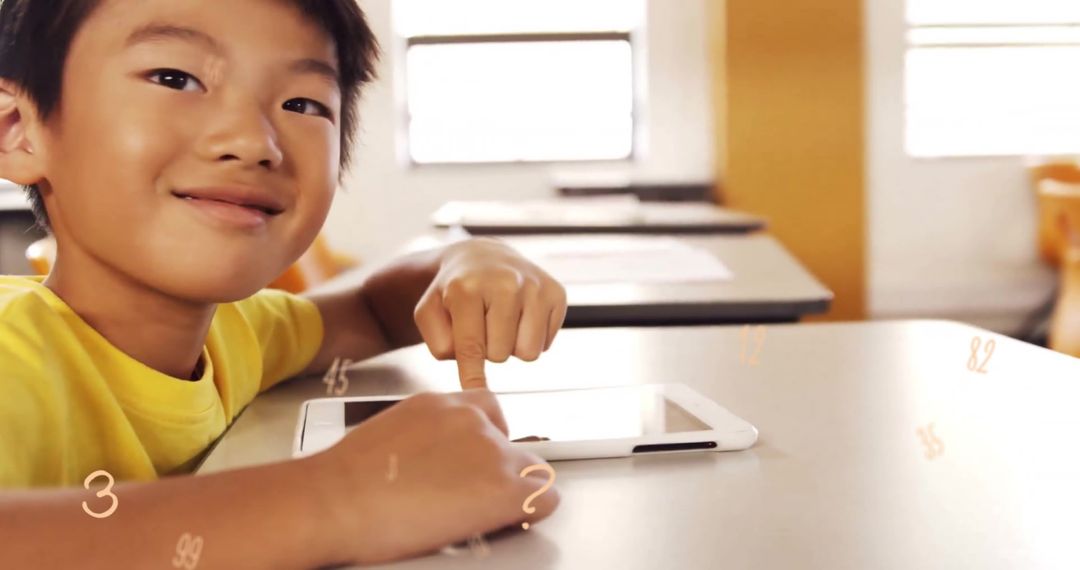 Smiling Asian Boy Engaged with Digital Tablet in Classroom