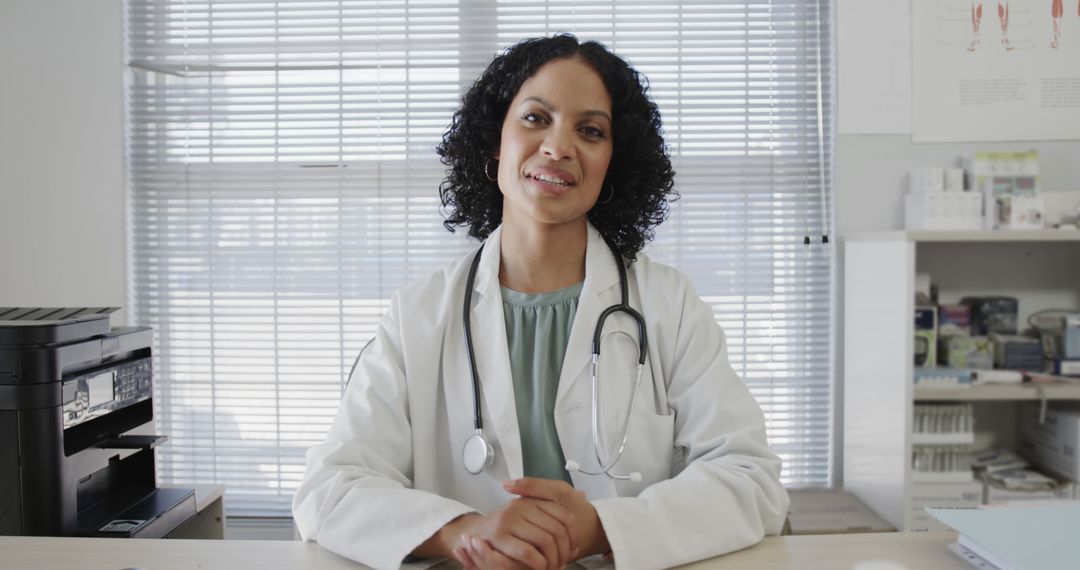 Smiling Female Doctor Sitting at Desk in Office - Free Images, Stock Photos and Pictures on Pikwizard.com