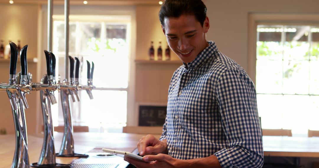 Young Bartender Using Digital Tablet in Modern Bar Setting - Free Images, Stock Photos and Pictures on Pikwizard.com