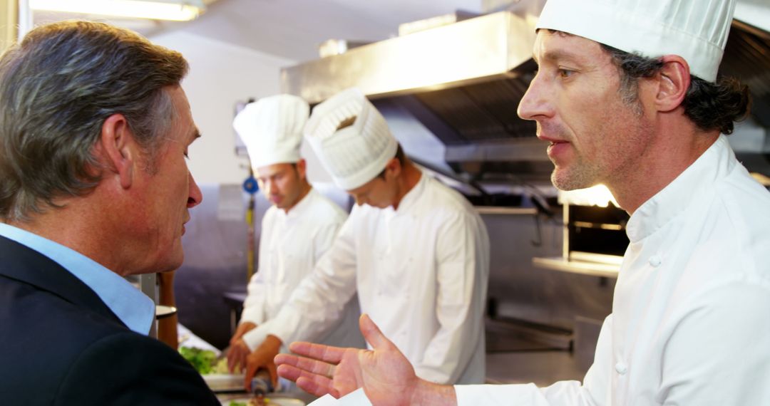 Chef Discussing With Manager In Busy Restaurant Kitchen - Free Images, Stock Photos and Pictures on Pikwizard.com