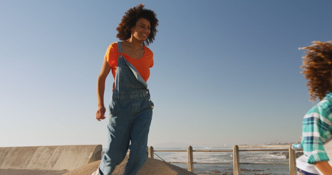 Woman in Denim Overalls Having Fun Outdoors by Seaside - Free Images, Stock Photos and Pictures on Pikwizard.com