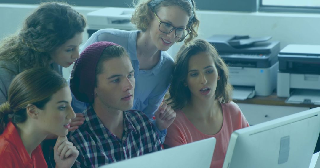 Young creative team collaborating around dual monitors in modern office workspace