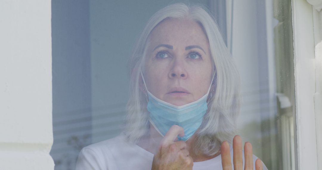 Older Woman Looking Out Window Wearing Mask with Concern - Free Images, Stock Photos and Pictures on Pikwizard.com