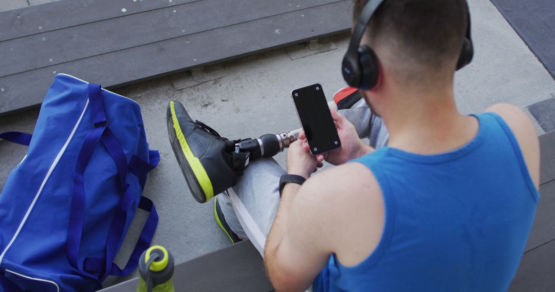 Athlete with Prosthetic Leg Relaxing with Smartphone After Workout - Free Images, Stock Photos and Pictures on Pikwizard.com