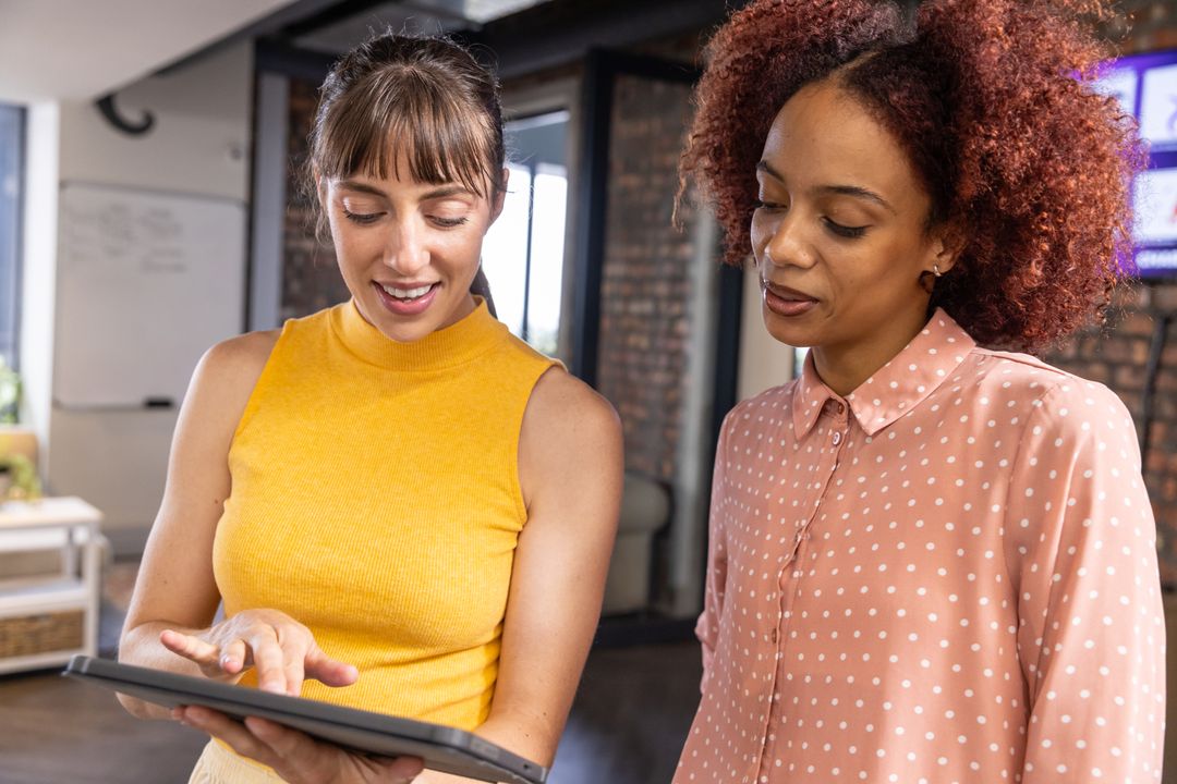 Diverse Female Professionals Collaborating with Tablet in Modern Workspace
