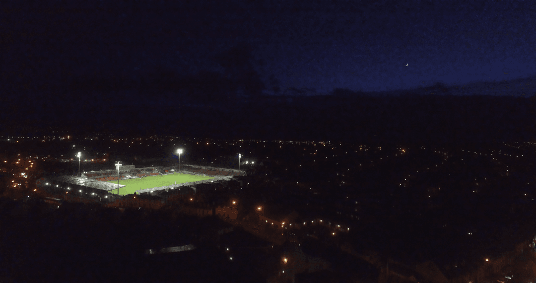 Illuminated Sports Field Night Aerial in Vibrant Cityscape
