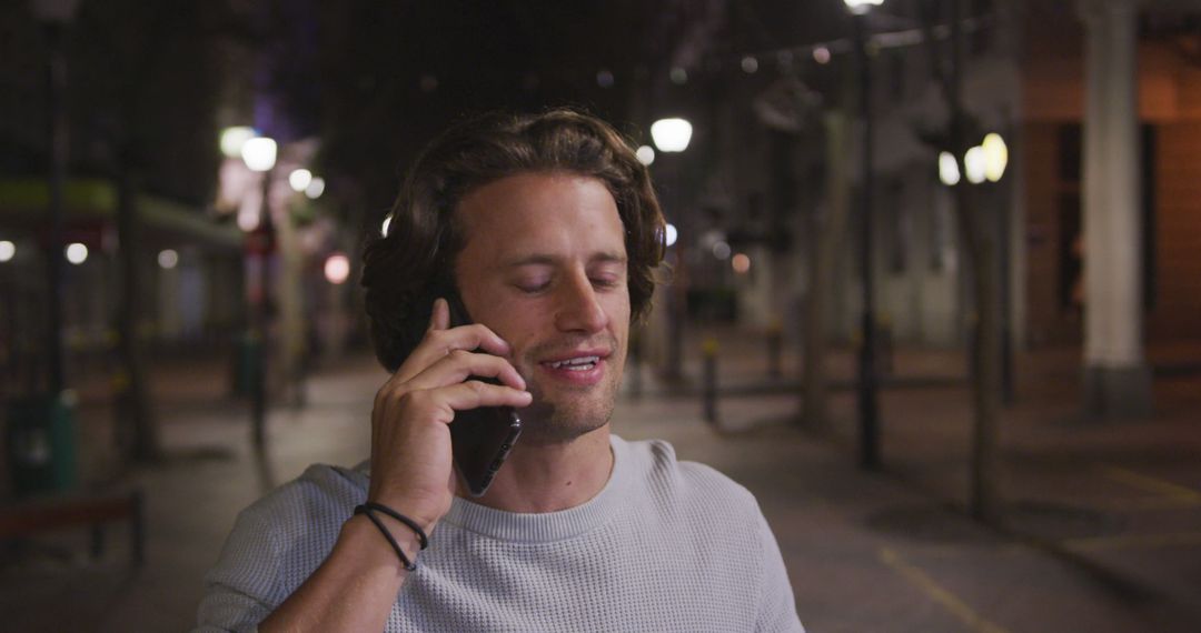 Young Man Smiling While Talking on Phone in Nighttime Urban Setting - Free Images, Stock Photos and Pictures on Pikwizard.com