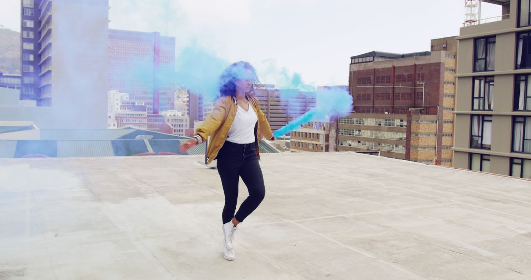 Young Woman Dancing with Blue Smoke on Urban Rooftop - Free Images, Stock Photos and Pictures on Pikwizard.com