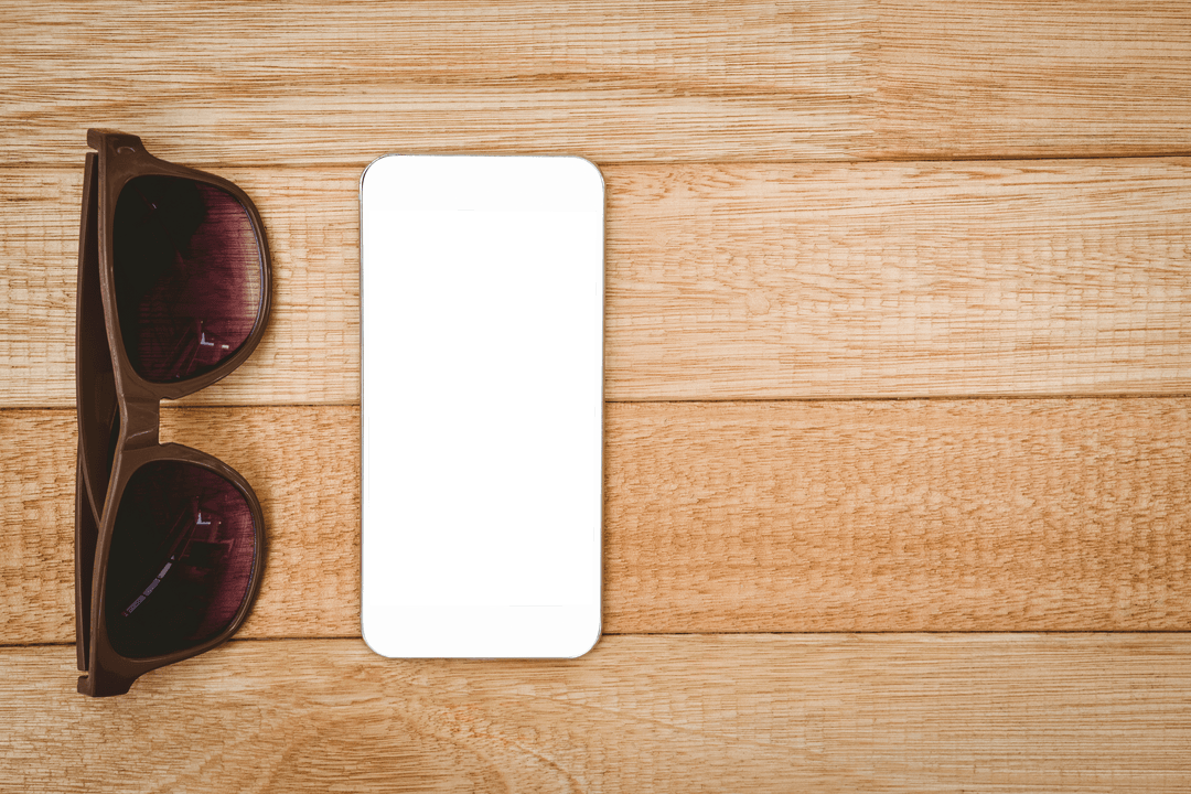Transparent smartphone with brown sunglasses on wooden desk