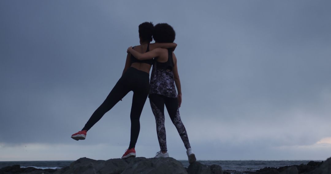 Two Women Embracing on Rocky Beach at Dusk - Free Images, Stock Photos and Pictures on Pikwizard.com