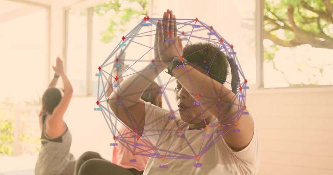 Practicing group yoga with focused woman pressing palms overhead in sunlit airy studio