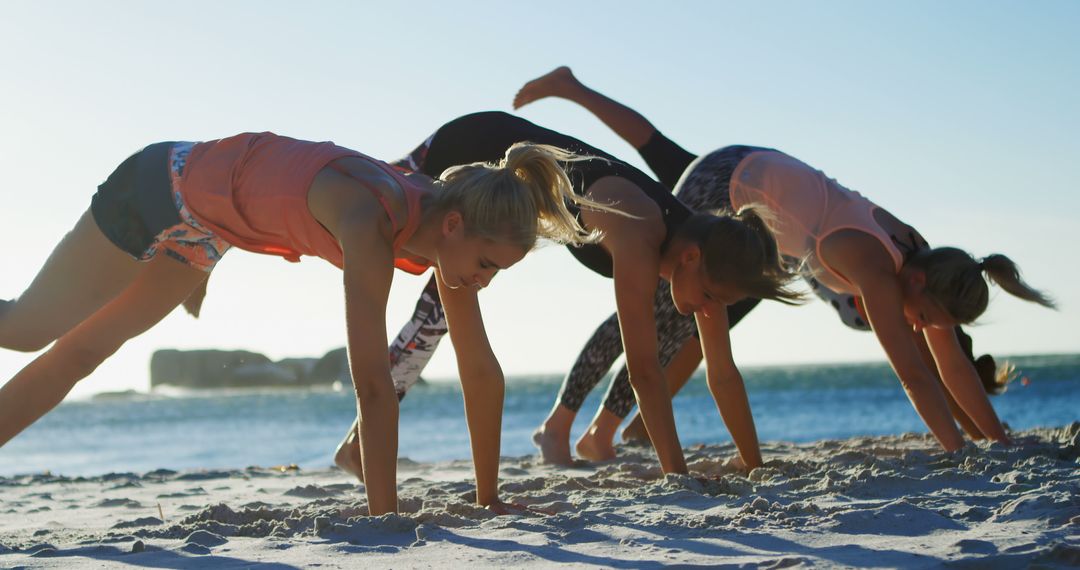 Three women practicing yoga on beach during sunset - Free Images, Stock Photos and Pictures on Pikwizard.com