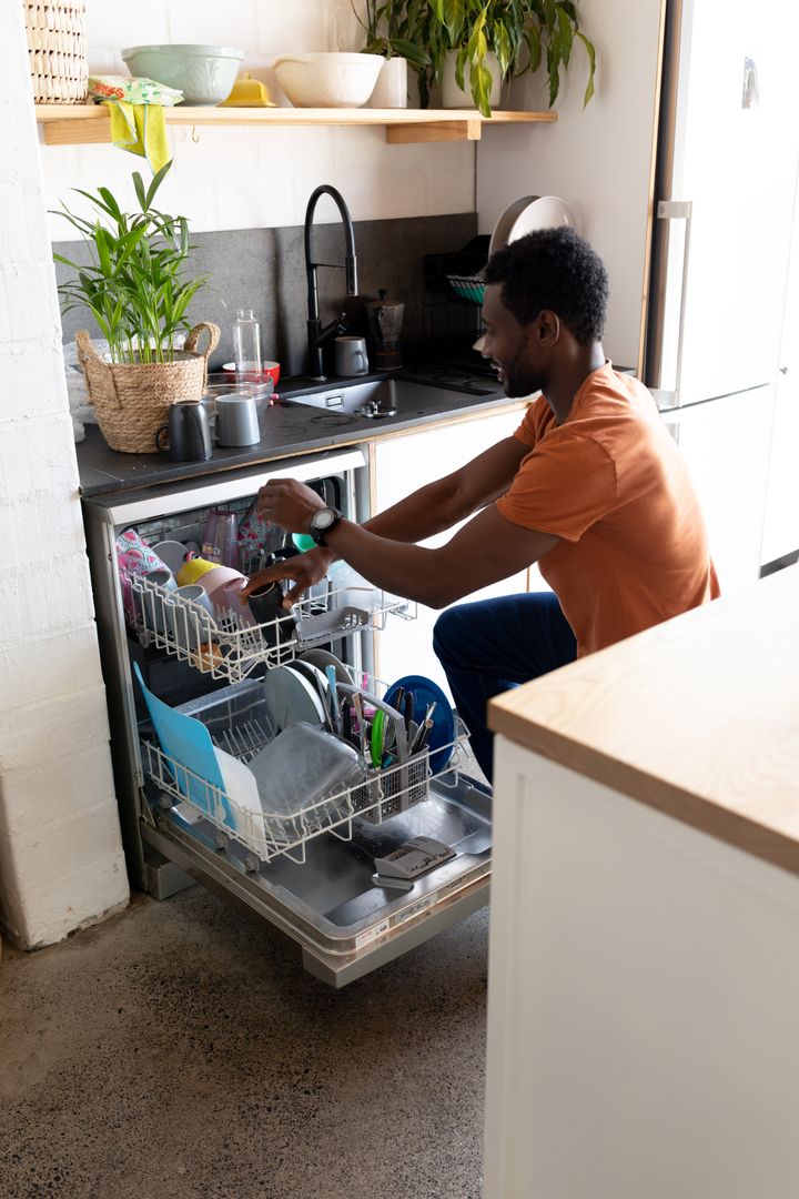 Happy African American Man Emptying Dishwasher at Home - Free Images, Stock Photos and Pictures on Pikwizard.com