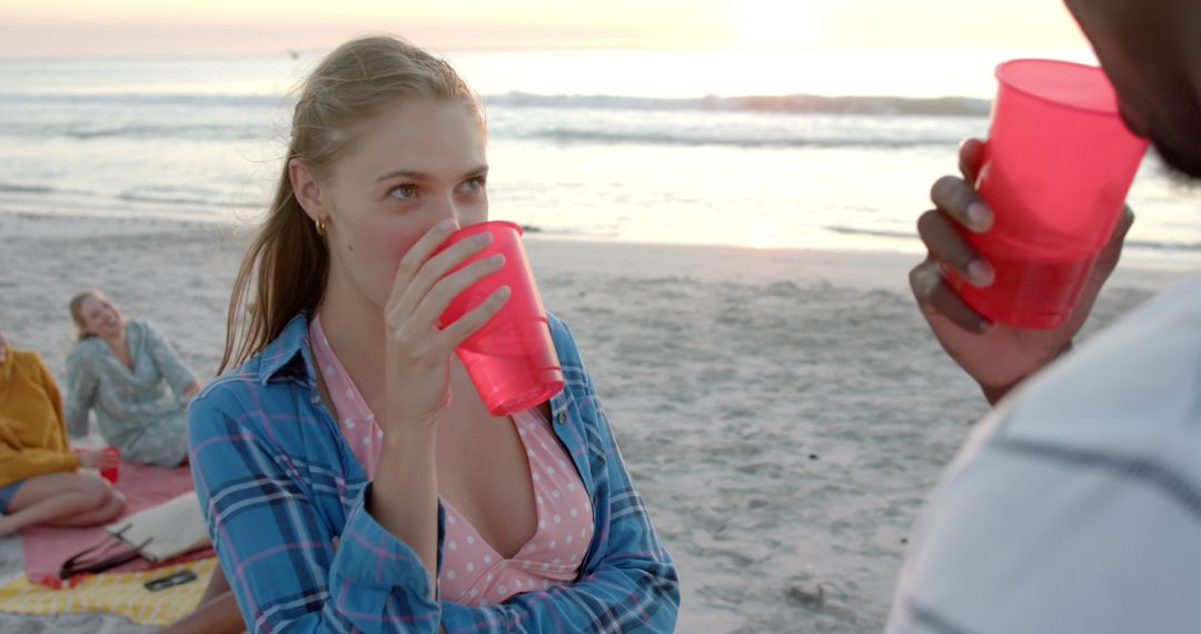 Friends Enjoying Sunset Beach Party with Red Cups