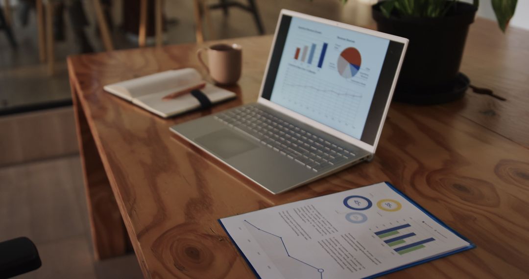 Laptop and Documents on Wooden Desk in Modern Office Setup