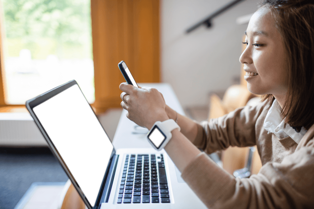 Young Woman Studying Using Phone and Laptop in Classroom Setting