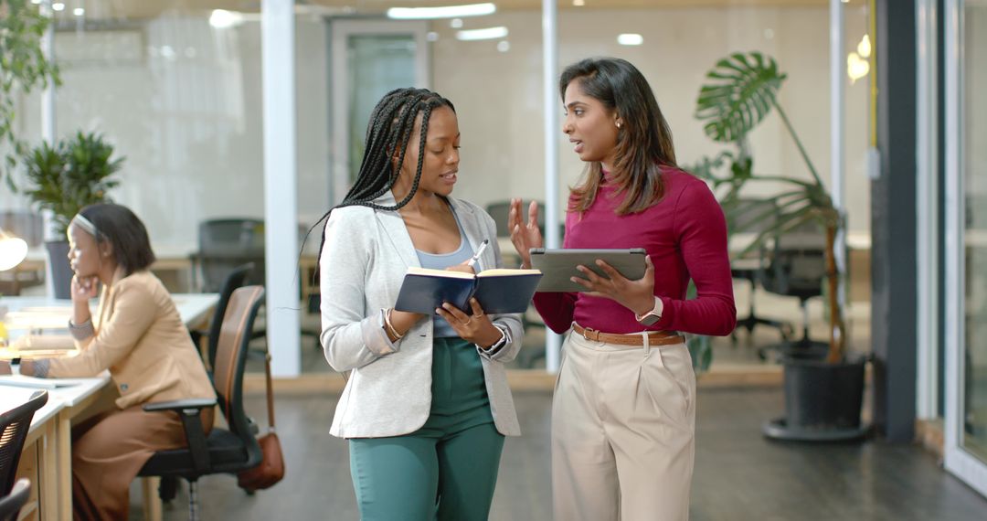 Diverse female coworkers collaborating while discussing project in modern open office
