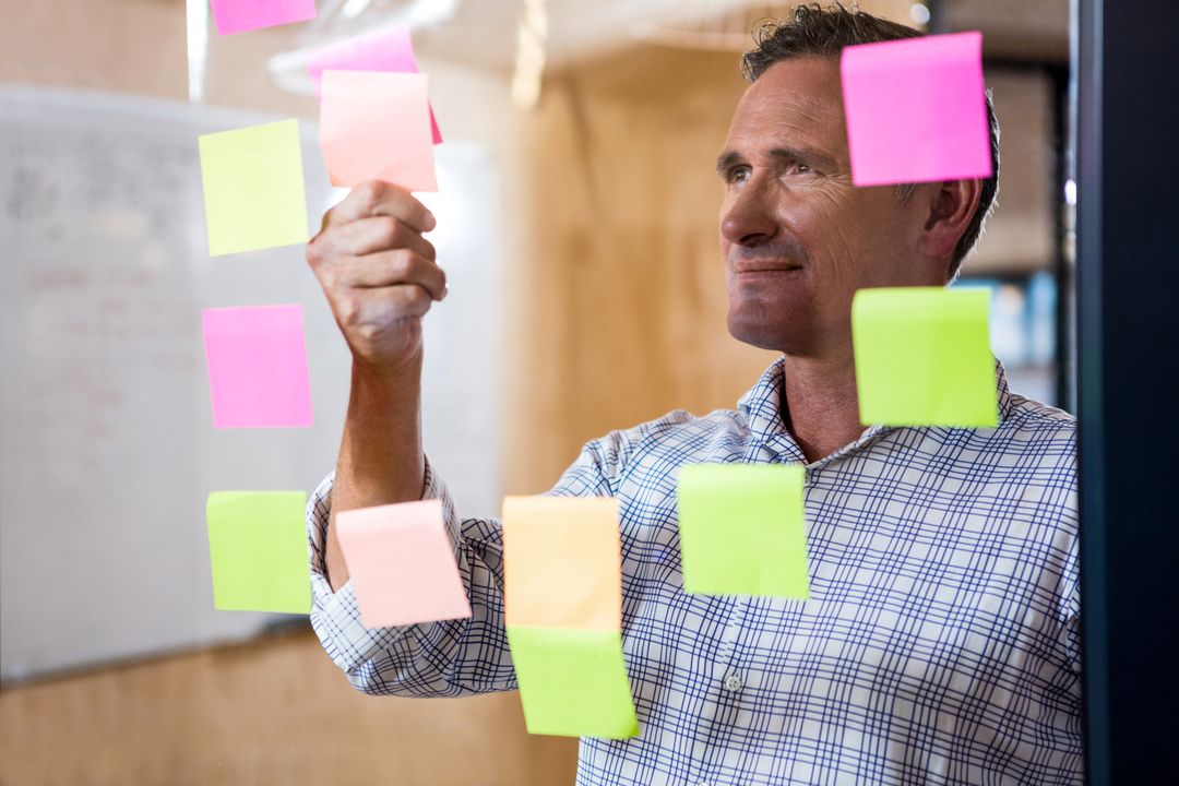 Man looking at sticky notes on window - Free Images, Stock Photos and Pictures on Pikwizard.com